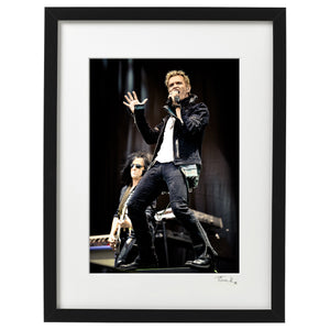 Framed music wall art print of singer Bill Idol and guitarist Steve Stevens onstage in pouring rain at Download festival 2010