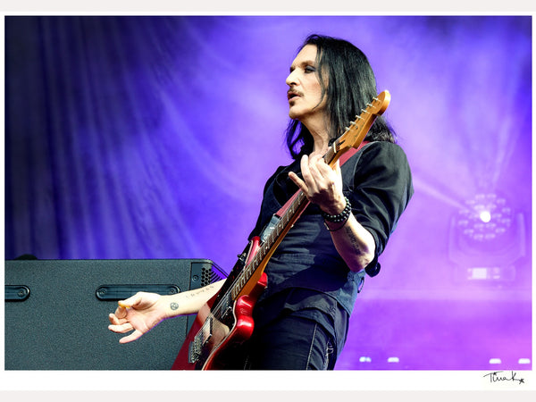 Photo print of Brian Molko of Placebo playing red guitar on stage at the MK Stadium, 2022. Signed by Tina K Photography.